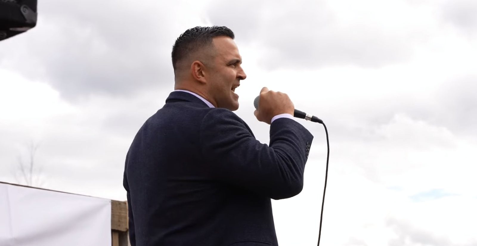 Garrett Soldano speaking into a microphone on an outdoor stage